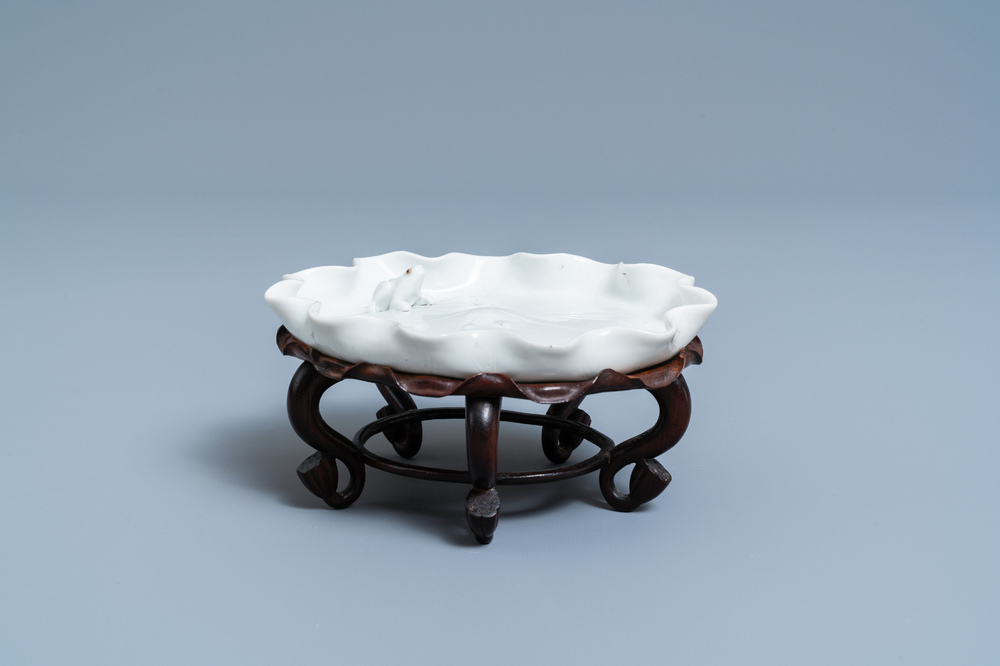 Un lave-pinceaux en porcelaine blanc de Chine figurant une grenouille sur fleur de lotus sur socle en bois sculpt&eacute;, Chine, Kangxi/Yongzheng
