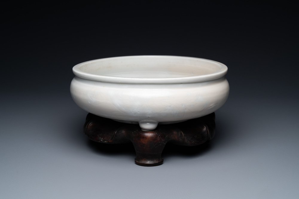 Un br&ucirc;le-parfum tripod &agrave; d&eacute;cor floral incis&eacute; en porcelaine blanc de Chine de Dehua sur socle en bois, Kangxi