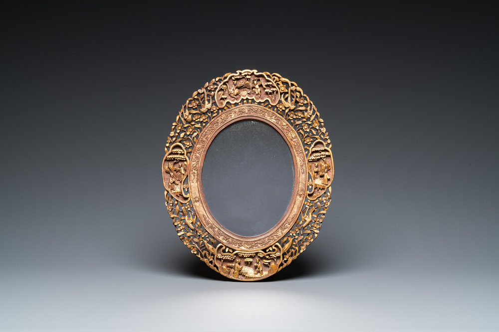 An oval Chinese reticulated gilded wooden mirror, 19/20th C.