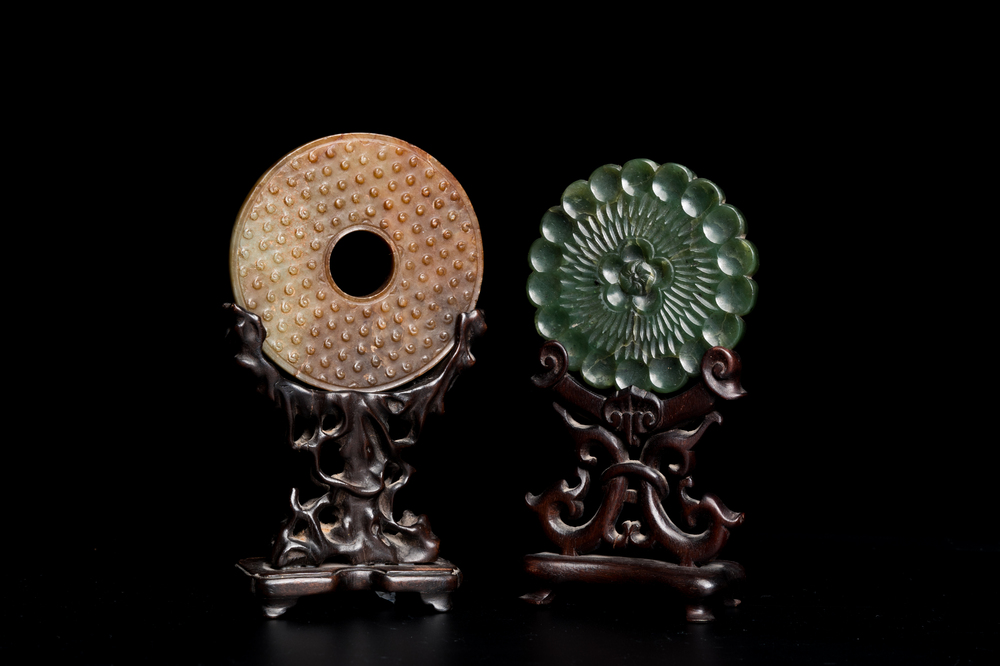 Un disque 'bi' en jade c&eacute;ladon et rouille et un pendentif en forme de fleur en jade vert sur socles en bois, Ming et Qing