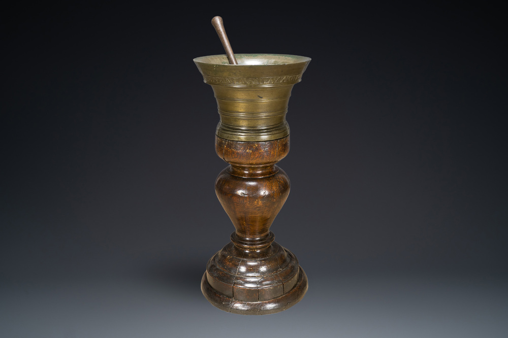 A large French bronze mortar and pestle on its carved oak base, dated 1631