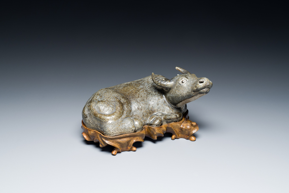 Een Chinese monochrome sculptuur van een liggende waterbuffel op houten sokkel, 19e eeuw