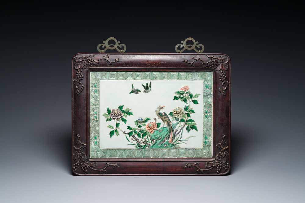 A Chinese relief-decorated famille verte 'peacock' plaque in a fine carved hongmu wooden frame, 19th C.