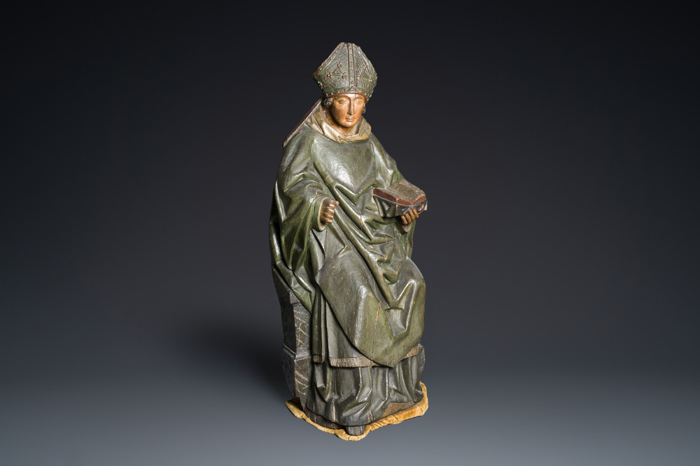 A large polychromed wood sculpture of a seated bishop, probably France, early 16th C.
