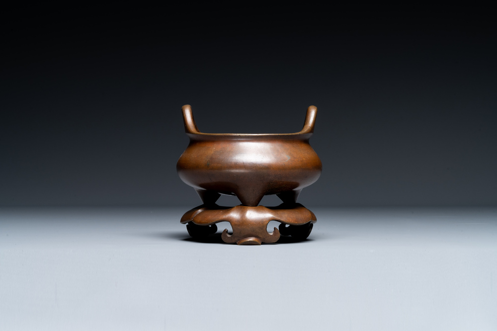 Een Chinees bronzen wierookvat met drie poten op een sokkel, Xuande merk, 19e eeuw