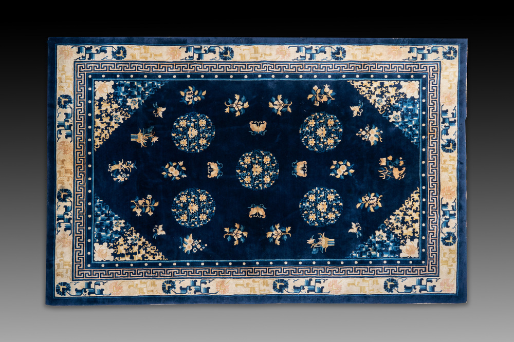 Een groot Chinees donkerblauw tapijt met bloemen en vlinders, 19/20e eeuw