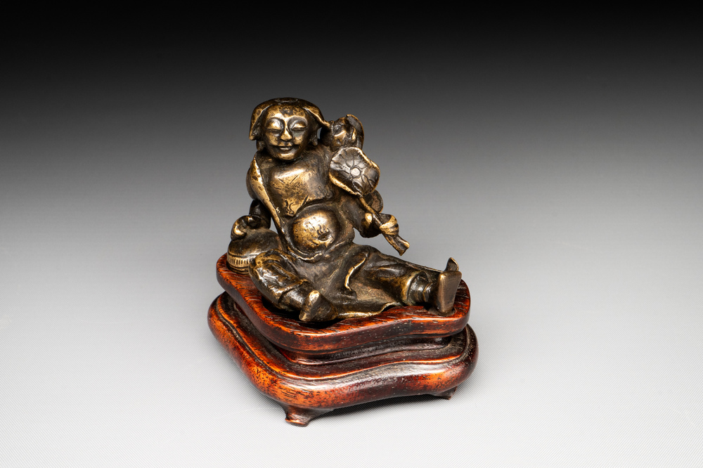 A Chinese bronze paperweight in the form of 'Shi De 拾得' on wooden stand, 16th C.