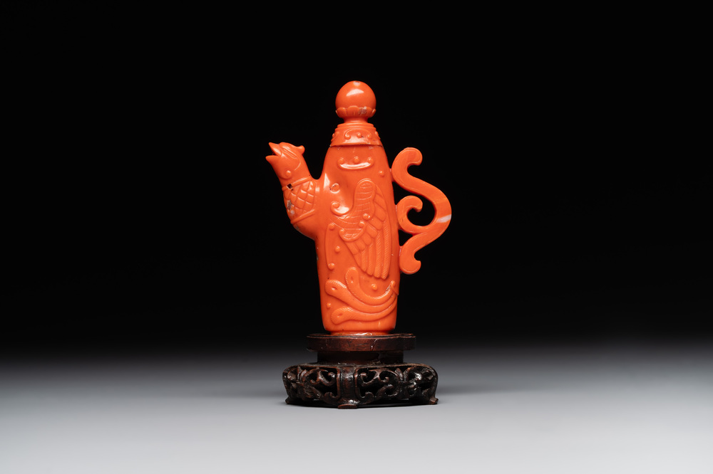 A Chinese carved red coral ewer and cover on wooden stand, 19th C.