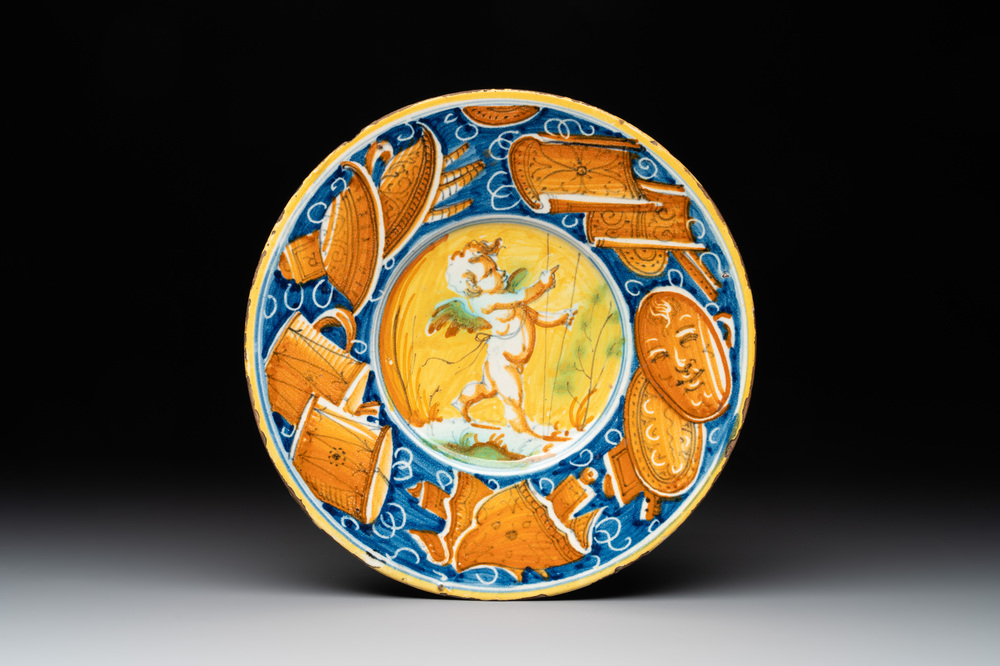 A polychrome Italian maiolica plate with a putto surrounded by trophies, Pesaro, 16th C.