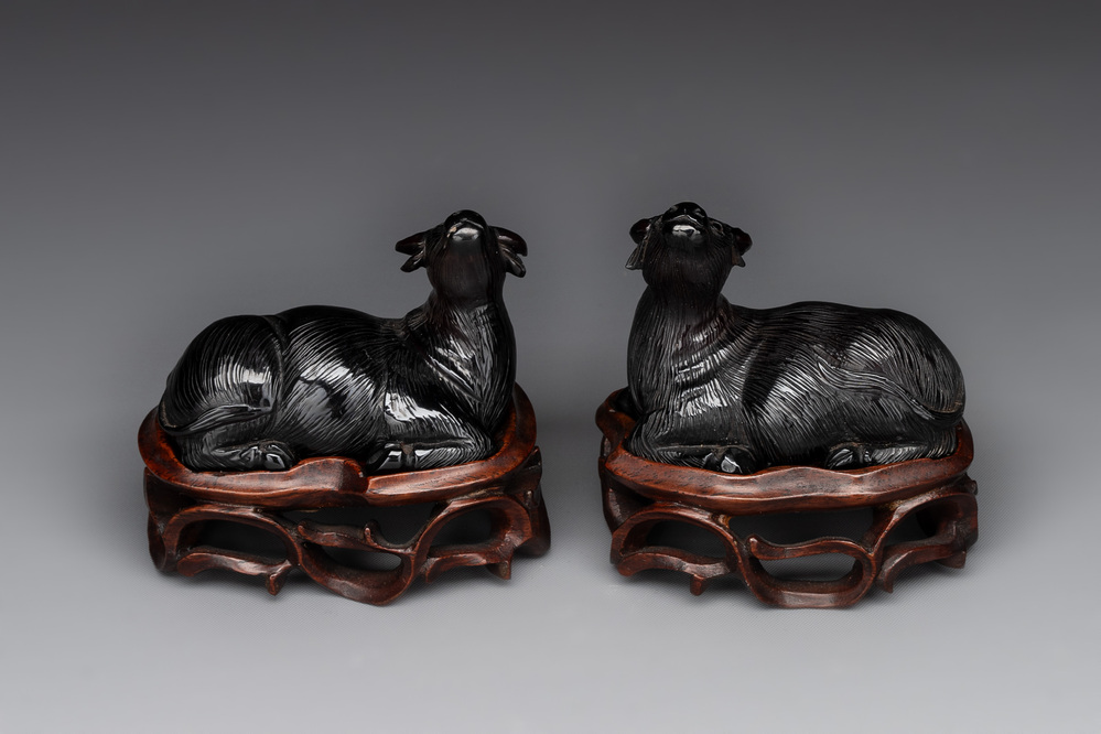 A pair of Chinese cherry amber or faturan recumbent oxen on wooden stands, Republic