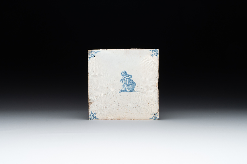 A blue and white Dutch Delft 'lady and pooping child' tile , 17th C.