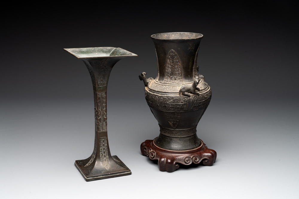 A Chinese archaistic bronze 'gu' vase and a 'hu' vase with rams in relief on a wooden stand, 18/19th C.