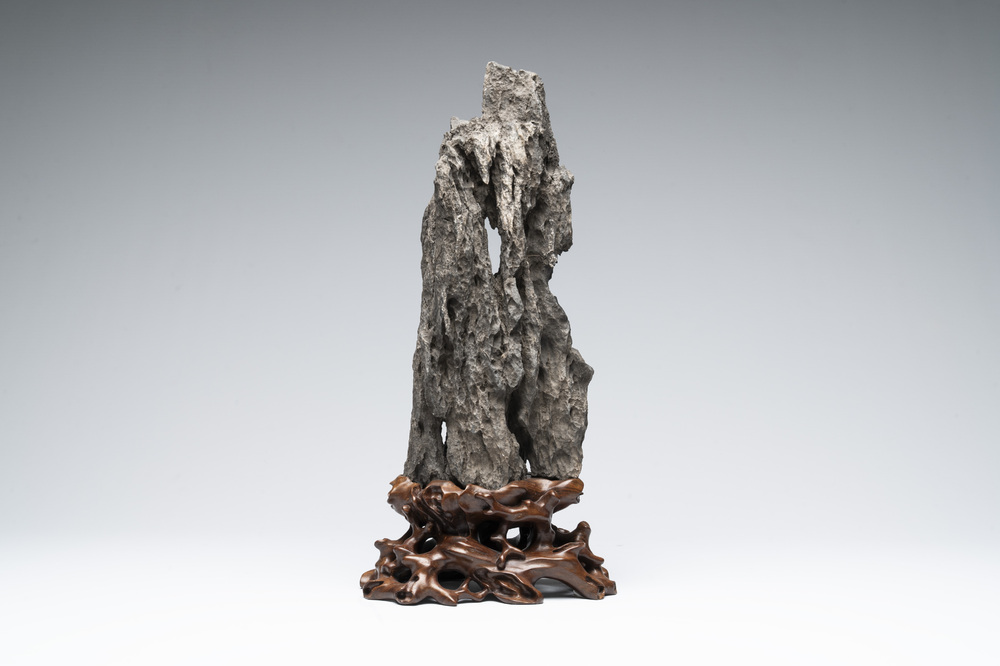 A Chinese ying stone scholar's rock on wooden stand, 20th C.