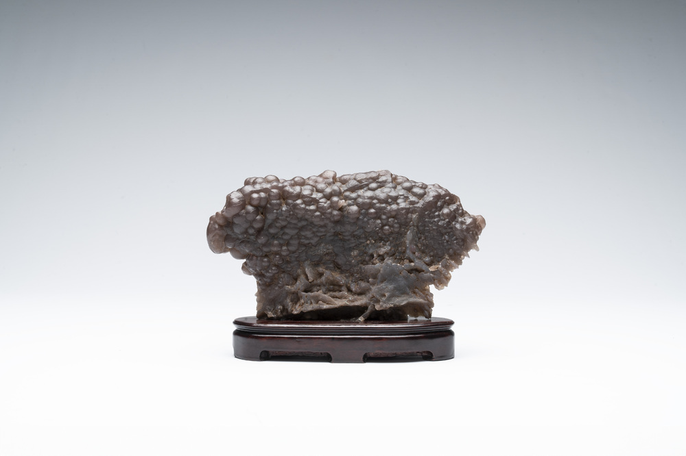 A Chinese grape agate scholar's rock on wooden stand, 20th C.