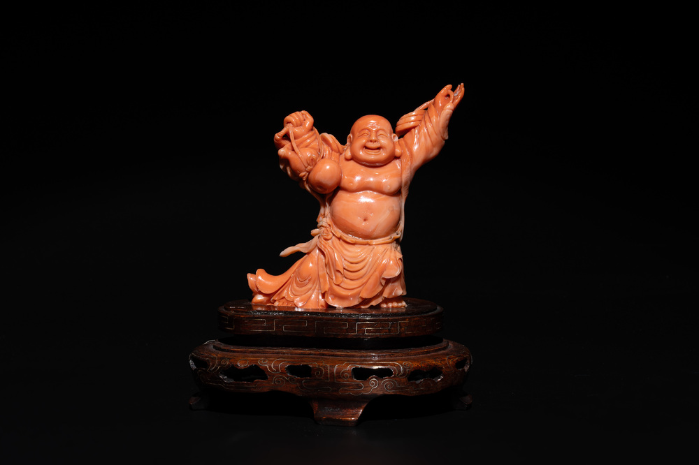 A Chinese red coral figure of a laughing Buddha on wooden stand, 19/20th C.