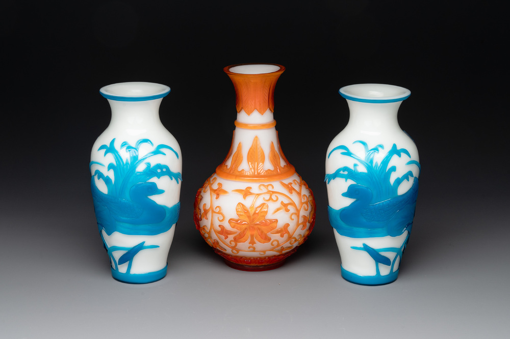 A pair of Chinese blue-overlay white Beijing glass vases with mandarin ducks and a orange-overlay white bottle vase, 19/20th C.