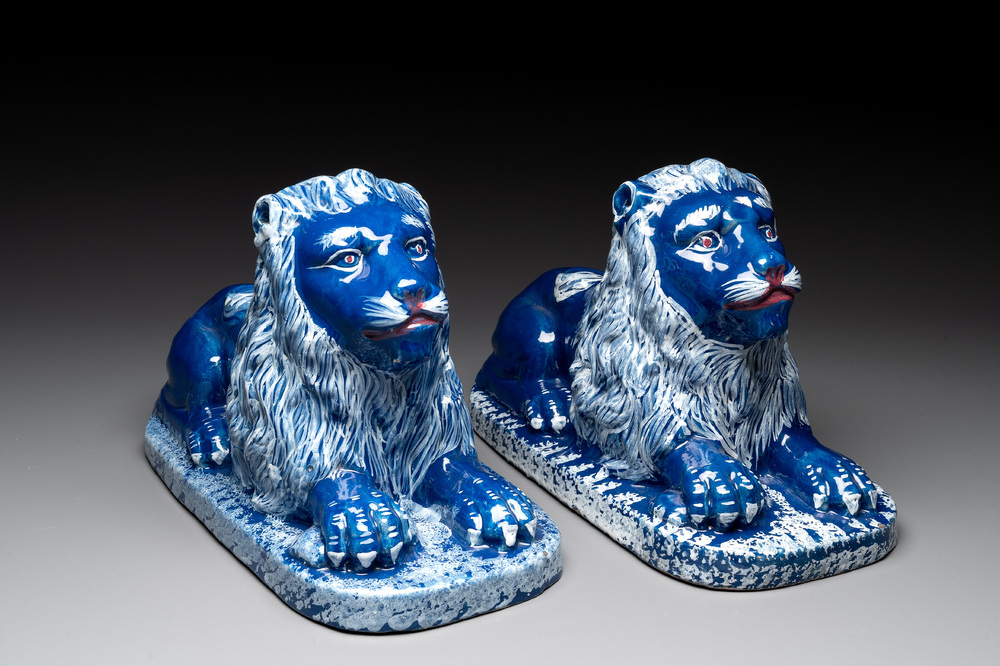 A pair of white-decorated blue-ground faience models of reclining lions, Nevers, 18th C.
