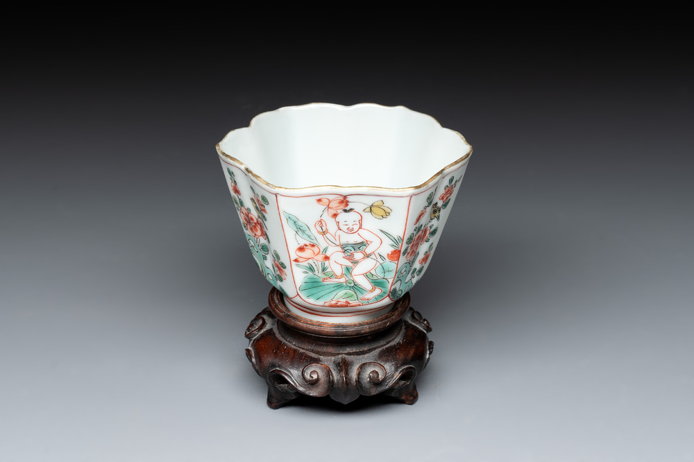A fine Chinese famille verte 'boy and lotus' flower-shaped cup and a wooden stand, Kangxi