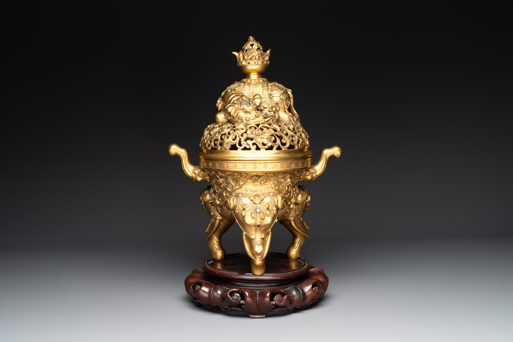A large Chinese precious stone-inlaid gilt bronze 'elephant' tripod censer and cover on wooden stand, 19th C.