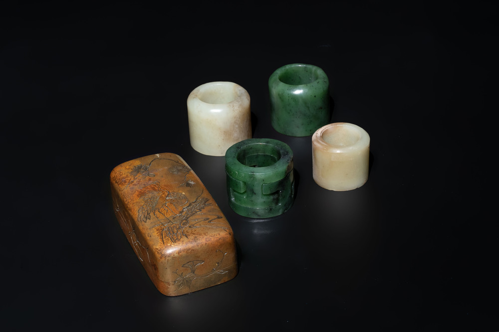 Four Chinese white and spinach-green jade archer rings and a bronze box with a crane design, 19th C.