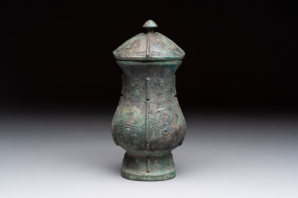 A Chinese archaic bronze food vessel and cover with taotie design, 'zhi 觶', Shang