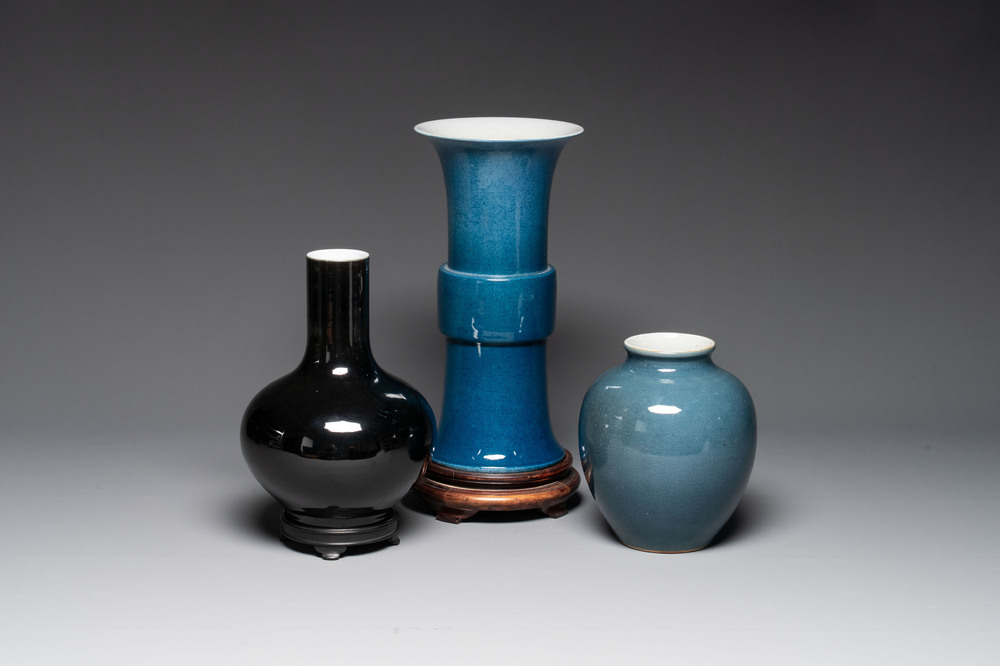 A Chinese black-glazed bottle vase, a blue-glazed jar and a powder-blue 'gu' vase on a wooden stand, Qianlong mark, 19/20th C.