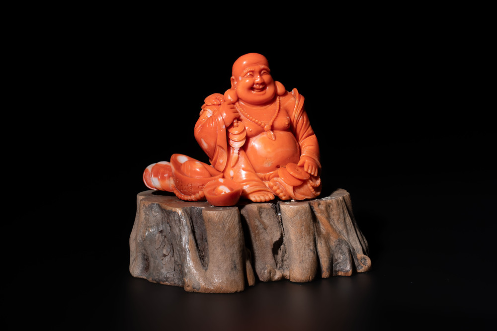 A Chinese red coral sculpture of a Milefo Buddha on wooden stand, 19/20th C.