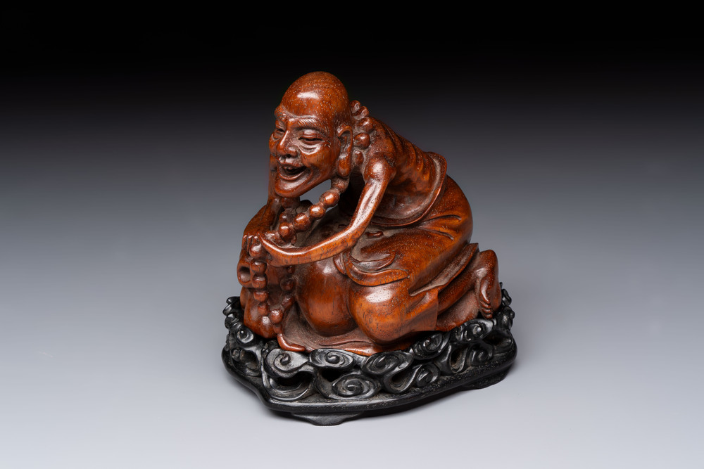 A Chinese fine huanghuali sculpture of a Luohan on a zitan stand, Qianlong mark, 19/20th C.