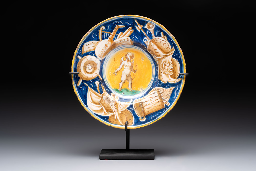 A polychrome Italian maiolica plate with Cupid holding an arrow, Casteldurante, dated 1560