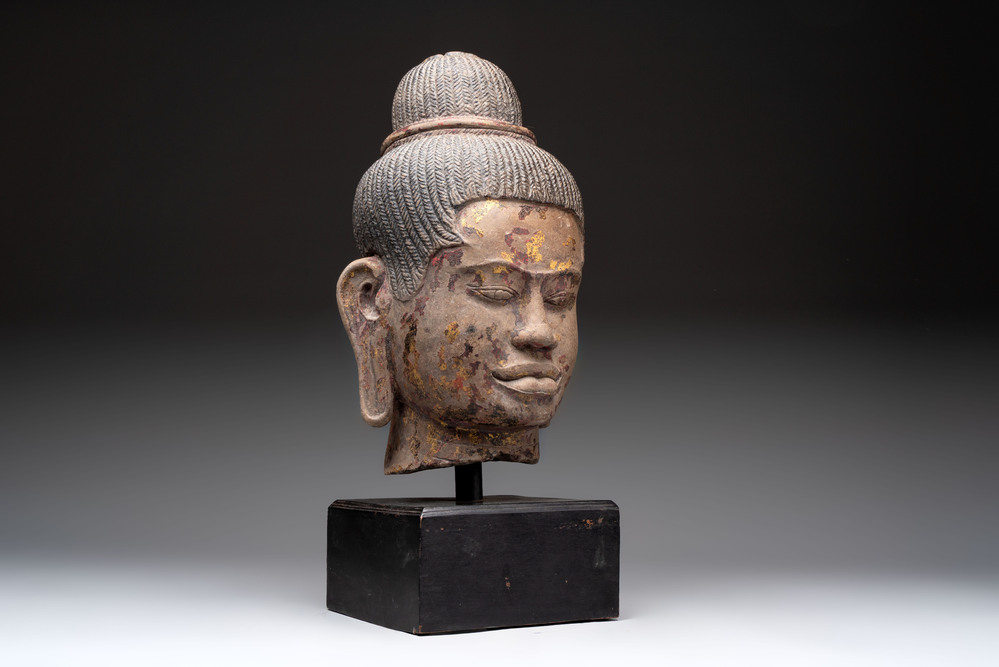 A Cambodian stone head of Shiva with braided hair and traces of gilt lacquer, Khmer Baphuon-style, 20th C.