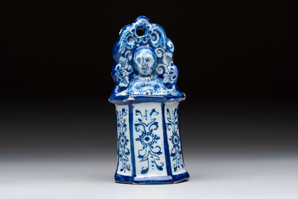 A blue and white Dutch Delft group of a child seated in a high chair, 18th C.