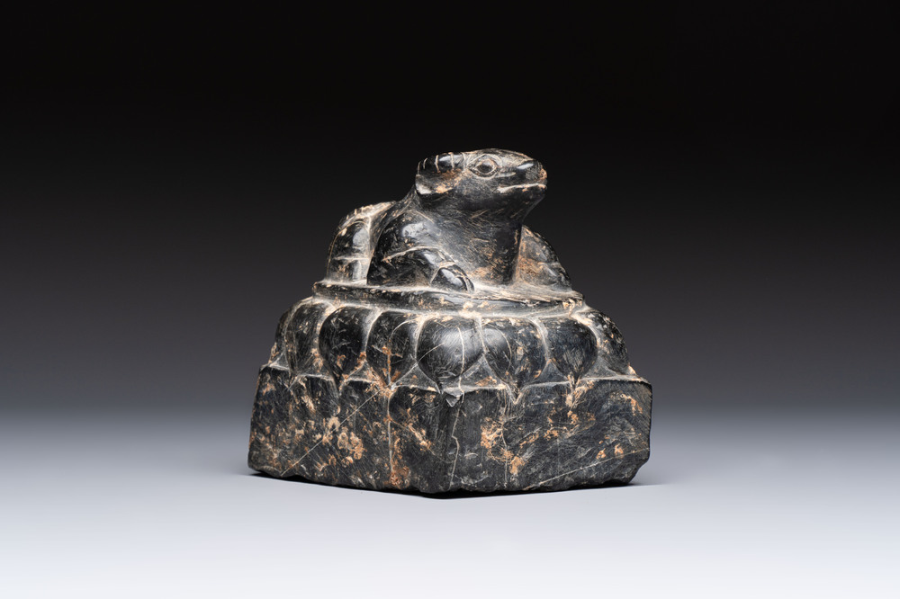 A Chinese carved black stone paper weight in the shape of a reclining buffalo on a lotus throne, Northern and Southern dynasties