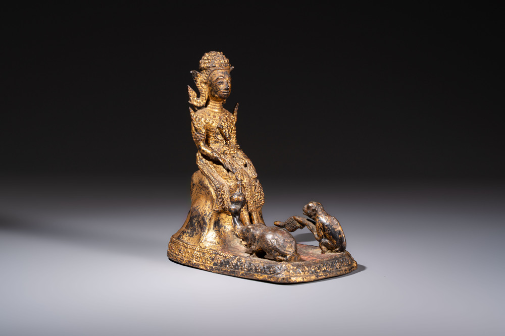 A Thai gilt-bronze figure of a seated deity with attendant animals, 19th C.