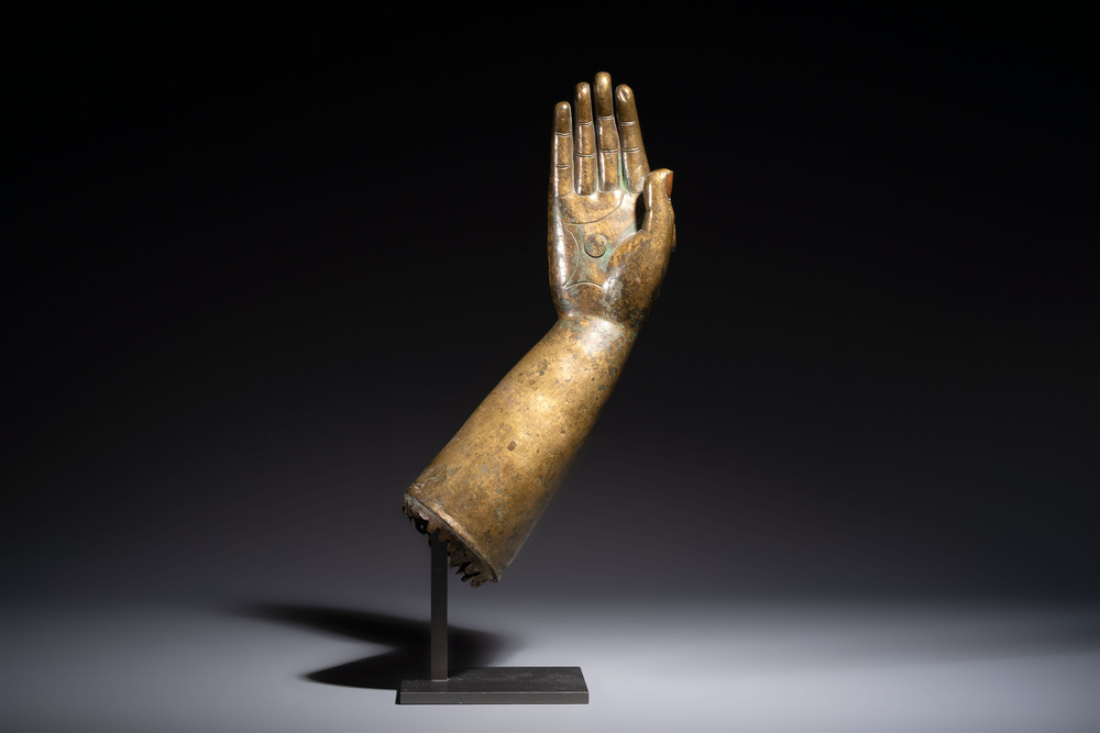 A rare and large Tibetan bronze forearm of a Buddhist figure with a chakra design, on a later metal stand, Qing