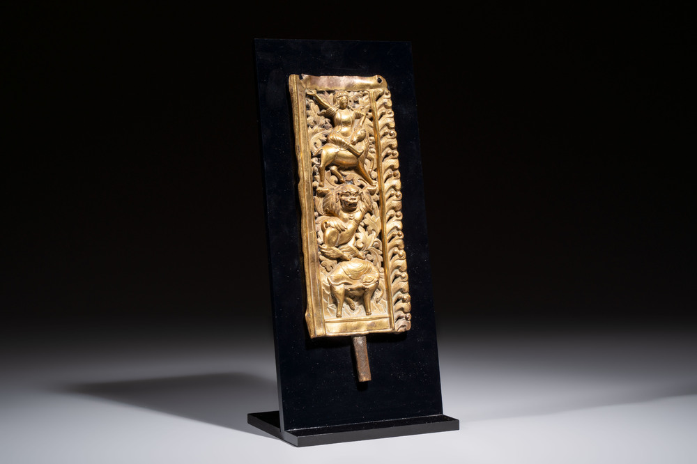A fine Tibetan gilt-copper repouss&eacute; plaque depicting a Dharmapala, a lion and an elephant, on a later mount, 18th C.