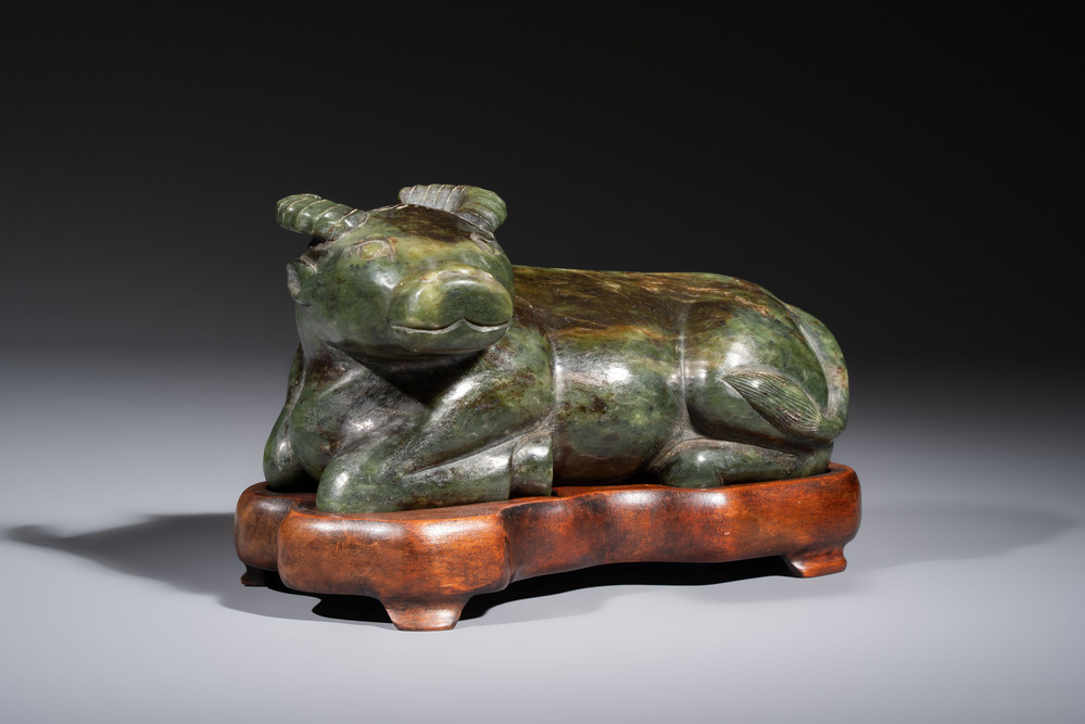 A Chinese green jade reclining buffalo on a wooden stand, 19/20th C.