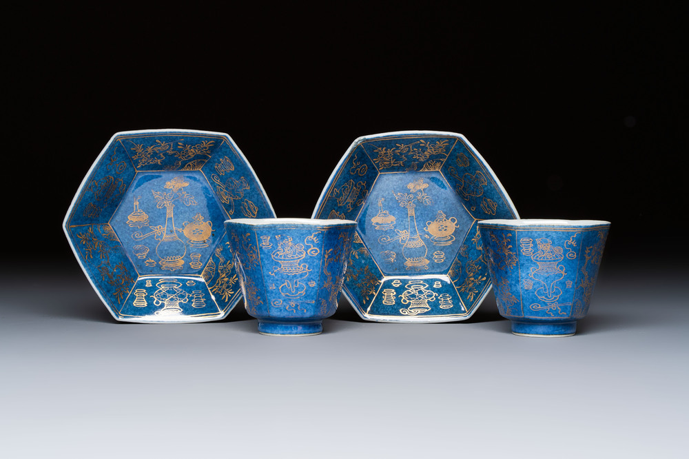 A pair of Chinese gilt-decorated powder-blue-ground 'Antiquities' cups and saucers, lingzhi mark, Kangxi