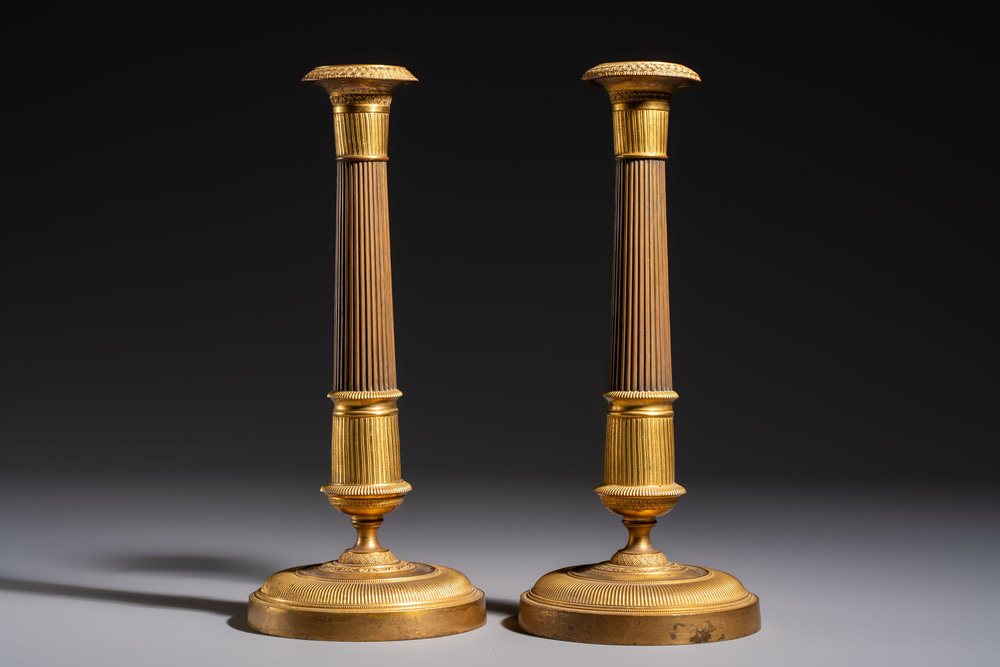 A pair of Empire parcel-gilt bronze candlesticks, early 19th C.