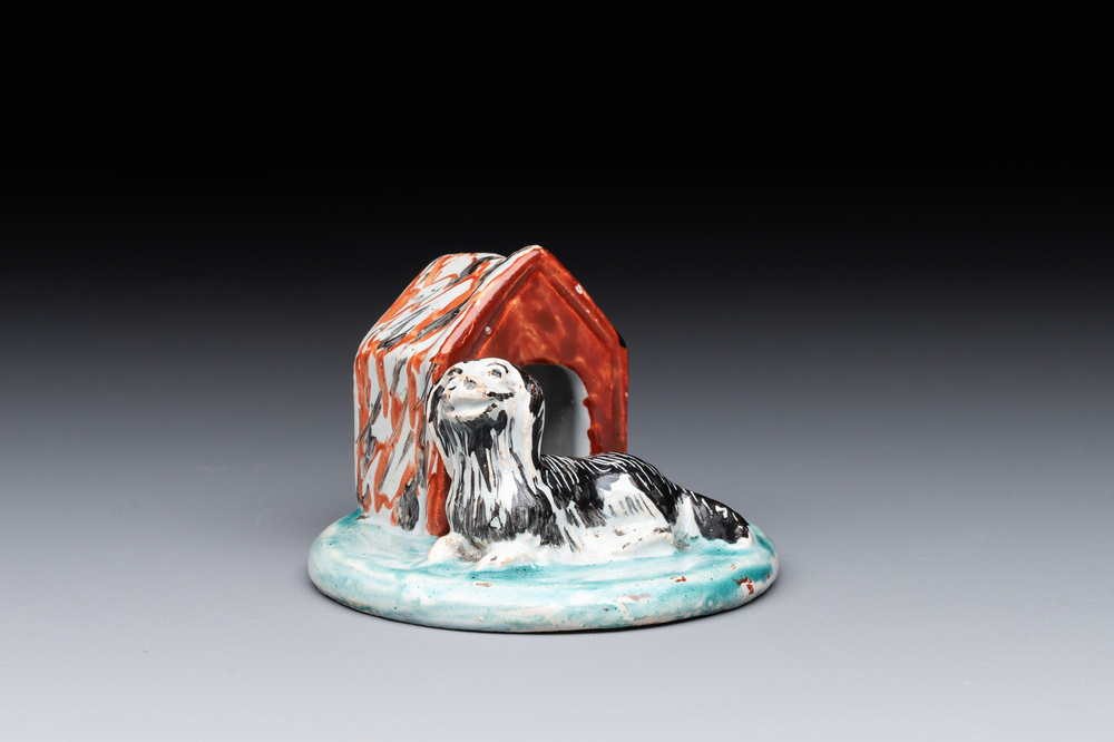 A rare polychrome Dutch Delft petit feu sculpture of a dog in front of its kennel, 18th C.