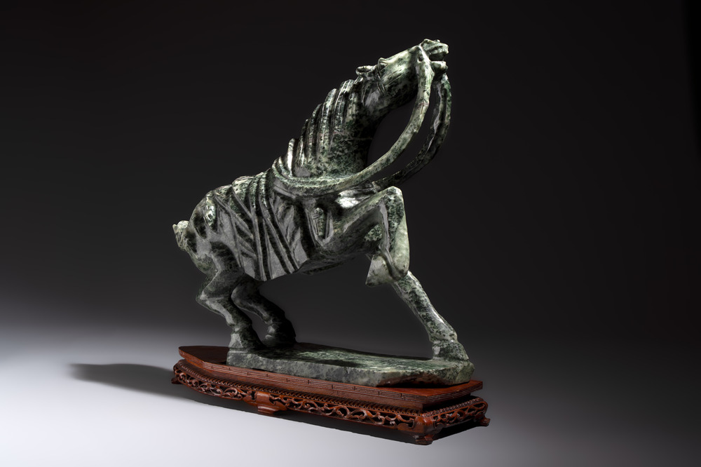 A large Chinese carved serpentine horse on a wooden stand, 20th C.