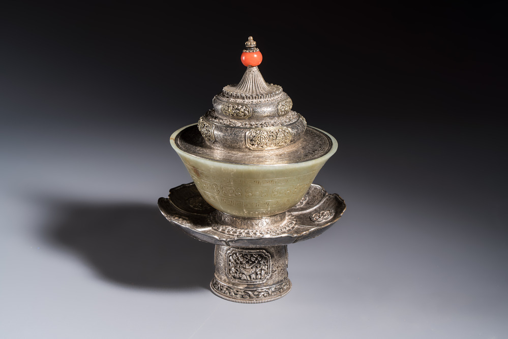 A Tibetan ritual jade bowl with a red coral-mounted silver cover and a stand, 19th C.