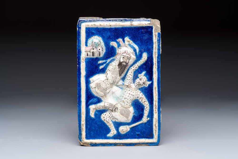 A Persian relief-moulded blue-ground tile depicting Fateh 'Ali Shah in the guise of Rustam slaying the White Div, Qajar, 19th C.