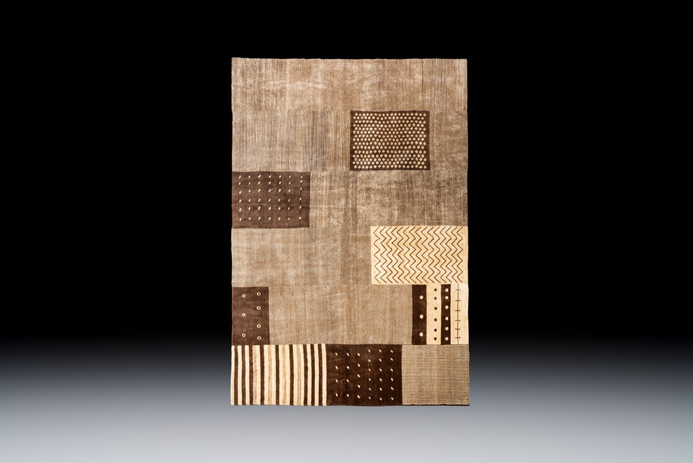 A large Persian hand-knotted woollen carpet with a geometric patchwork design, 20th C.
