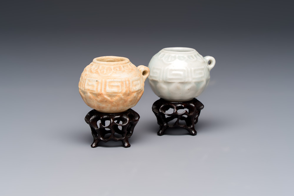 A pair of Chinese bird feeders with moulded design, one unglazed, on later wooden stands, Song