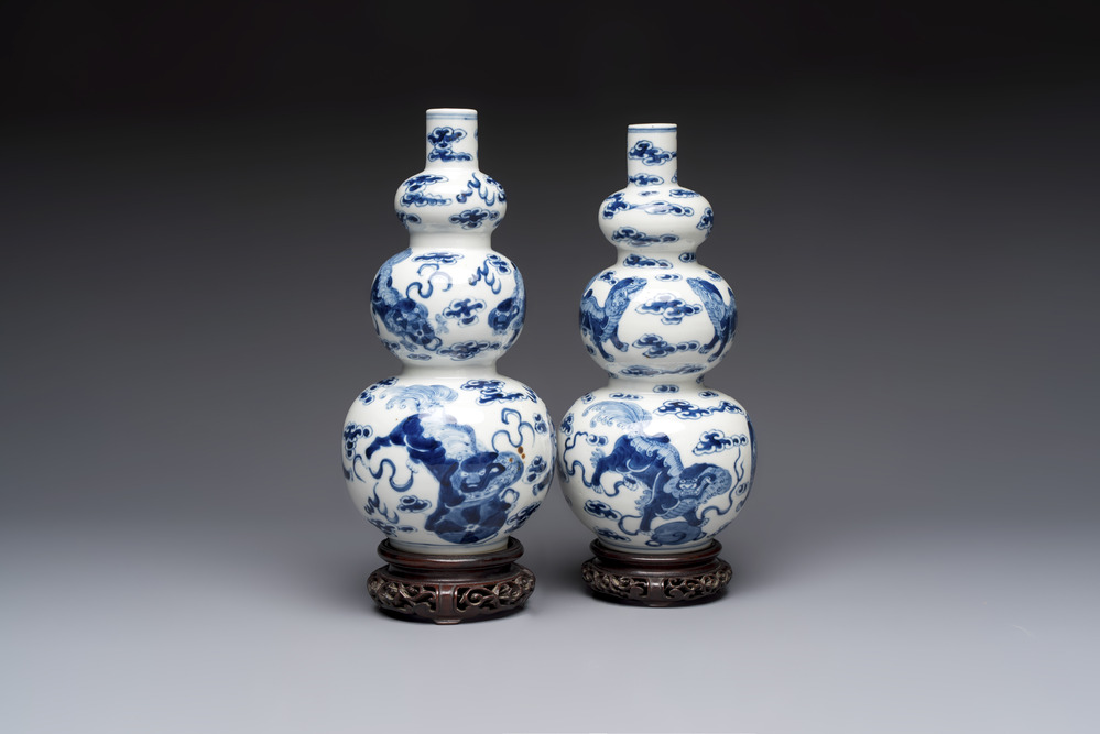 A pair of Chinese blue and white 'Buddhist Lions' triple gourd vases on reticulated wooden stands, 19th C.