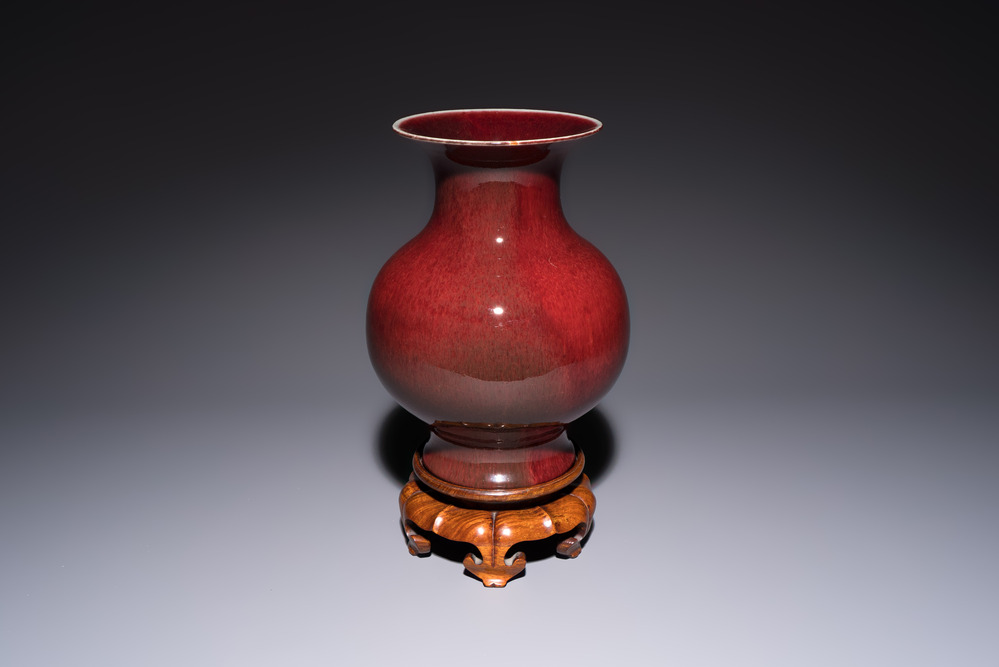 A Chinese copper-red-glazed vase on a wooden stand, 20th C.