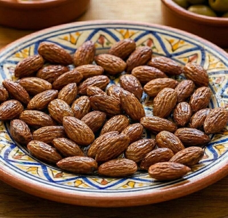 Saltrostade mandlar upplagda på ett keramikfat.